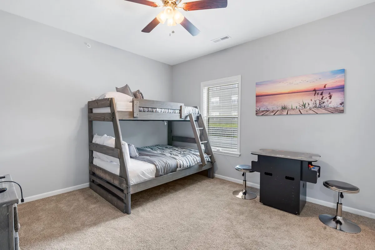 A playful bunk room with sturdy built-in bunks, cheerful wall art, and a small table with stools set up for games or creative activities. The ambiance is cozy and full of youthful energy, making it ideal for children’s sleepovers or playful moments for all ages.