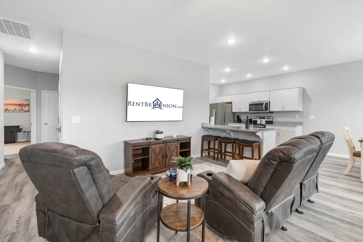 A cozy, inviting living space featuring reclining chairs, a large television, and a kitchen island visible in the background. The setup is perfect for movie nights or entertaining after a day of activities, with a focus on comfort and togetherness.